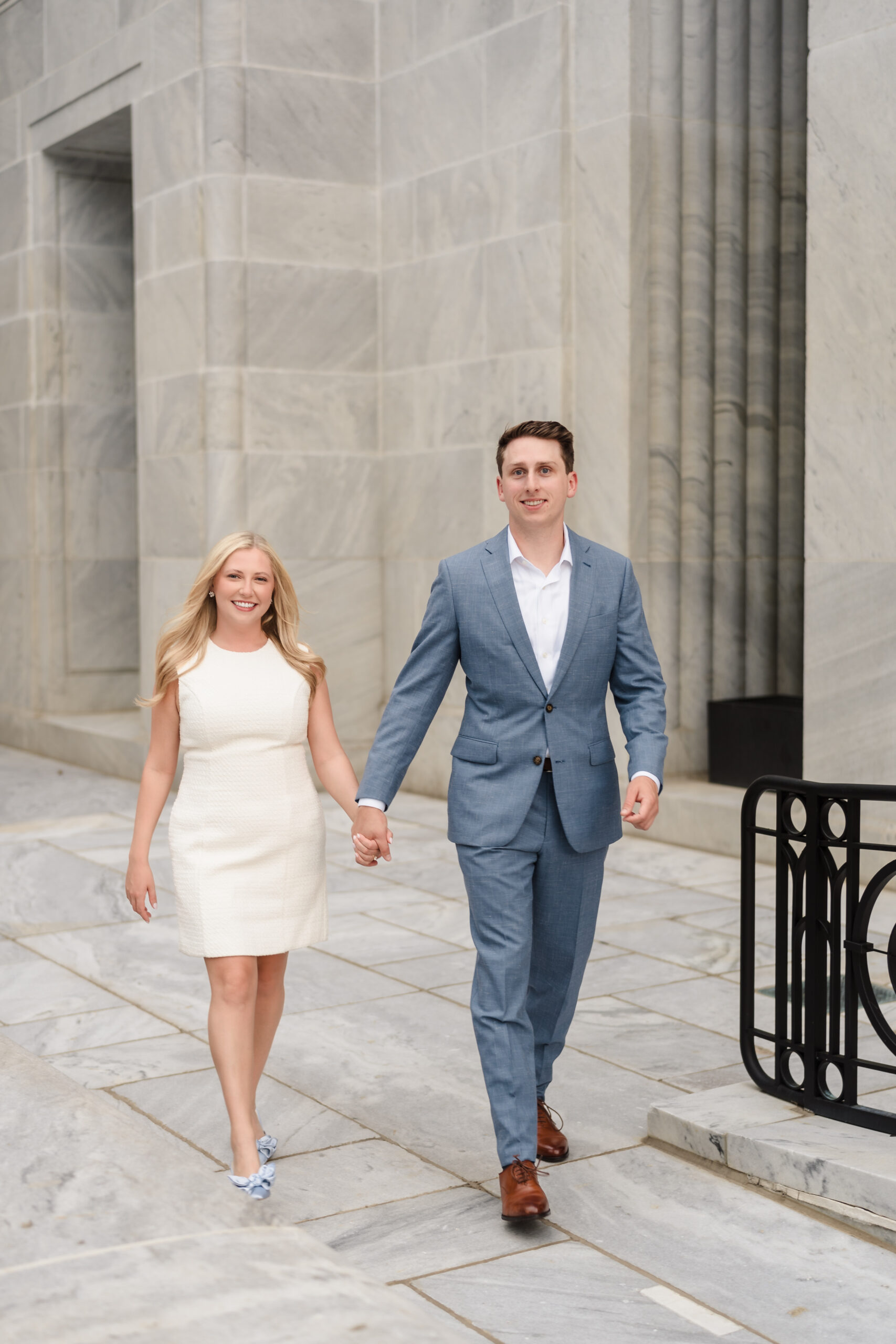 A man and woman hold hands and smile on the patio of the Ohio Supreme Court building