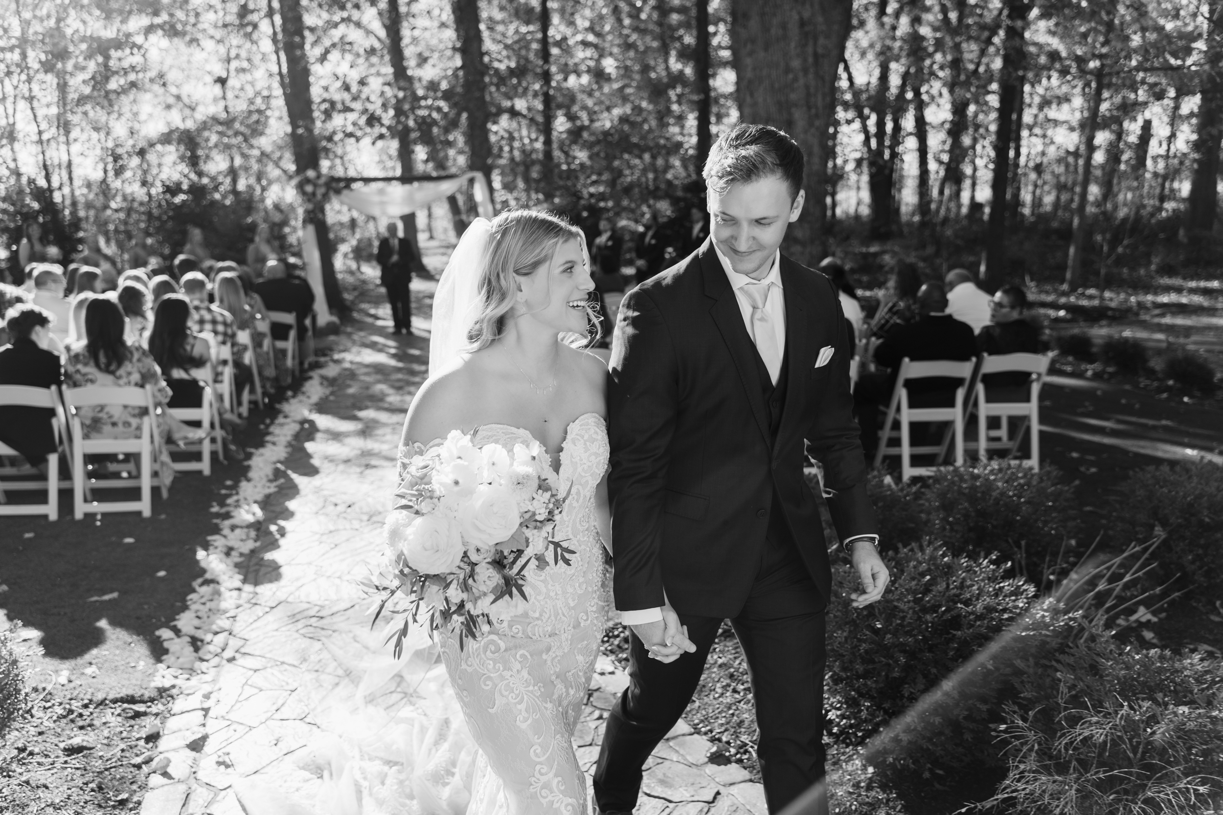 A bride and groom hold hands and smile as they exit their Columbus wedding ceremony