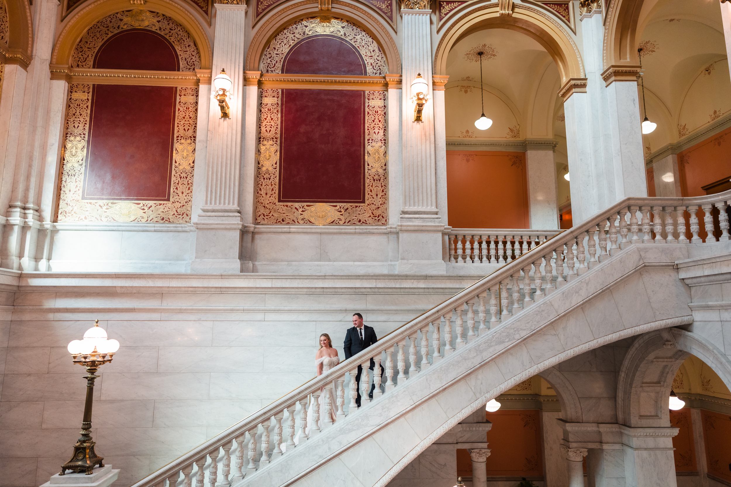 A bride and groom walk up the grand staircase inside the Ohio Statehouse